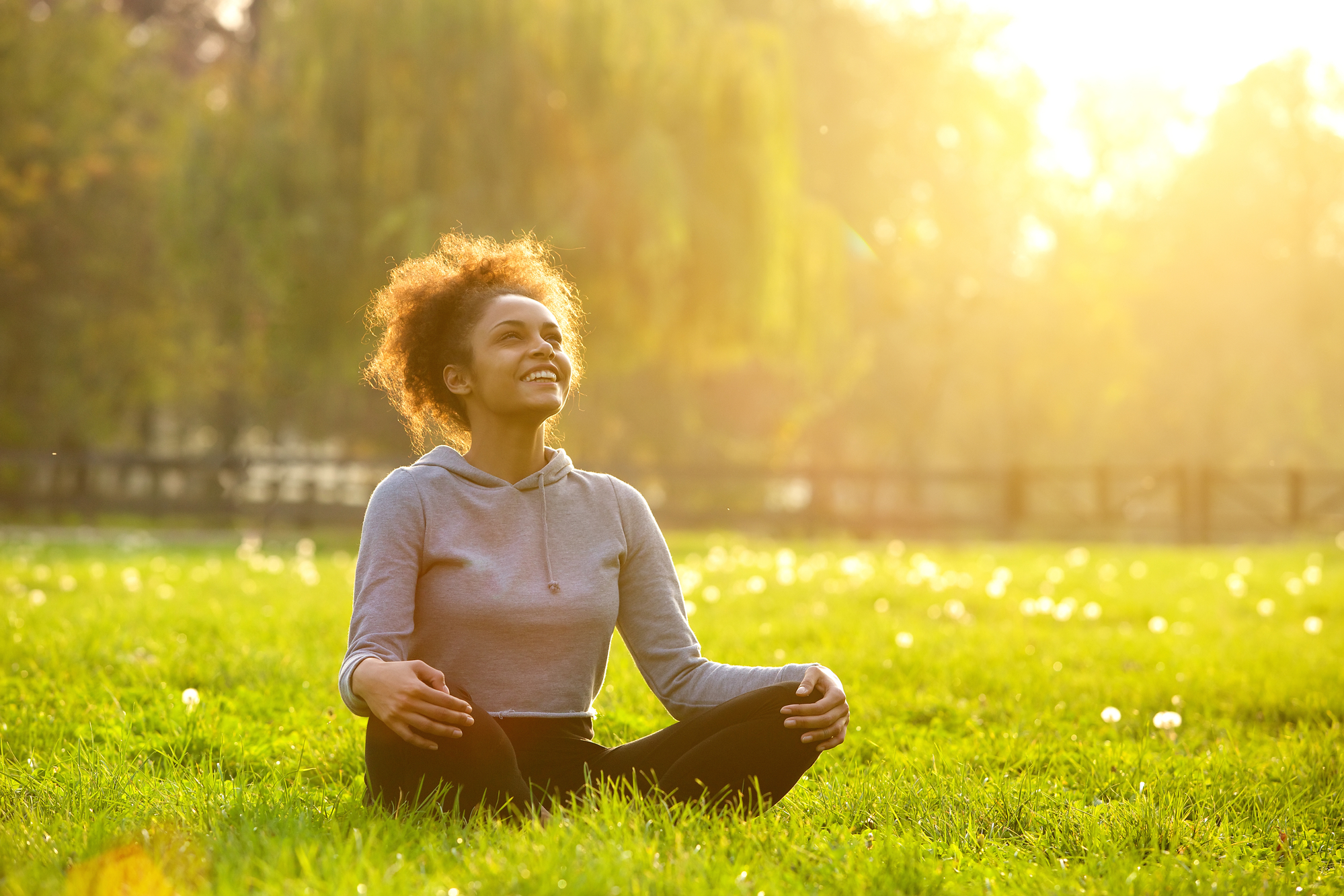 Woman meditating peacefully in sunlit green park