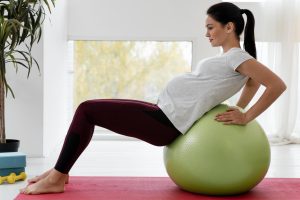 young pregnant woman exercising with a fitness ball