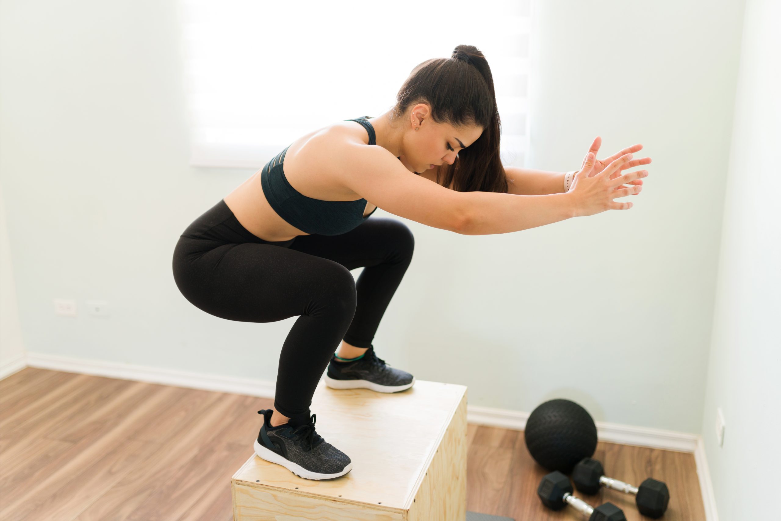 woman jumping doing squats plyo box